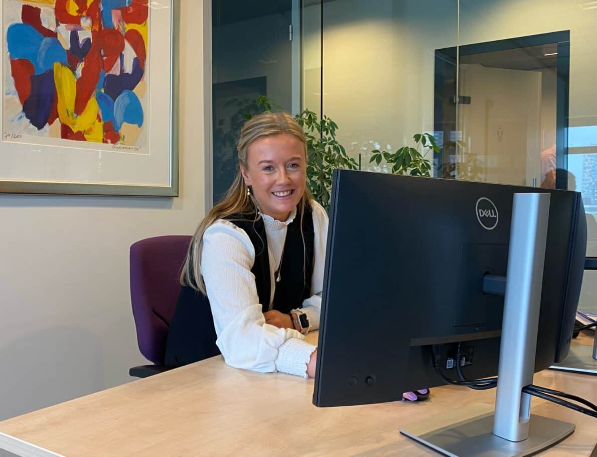 Vrouwlijke collega die lachend achter haar computer scherm zit.