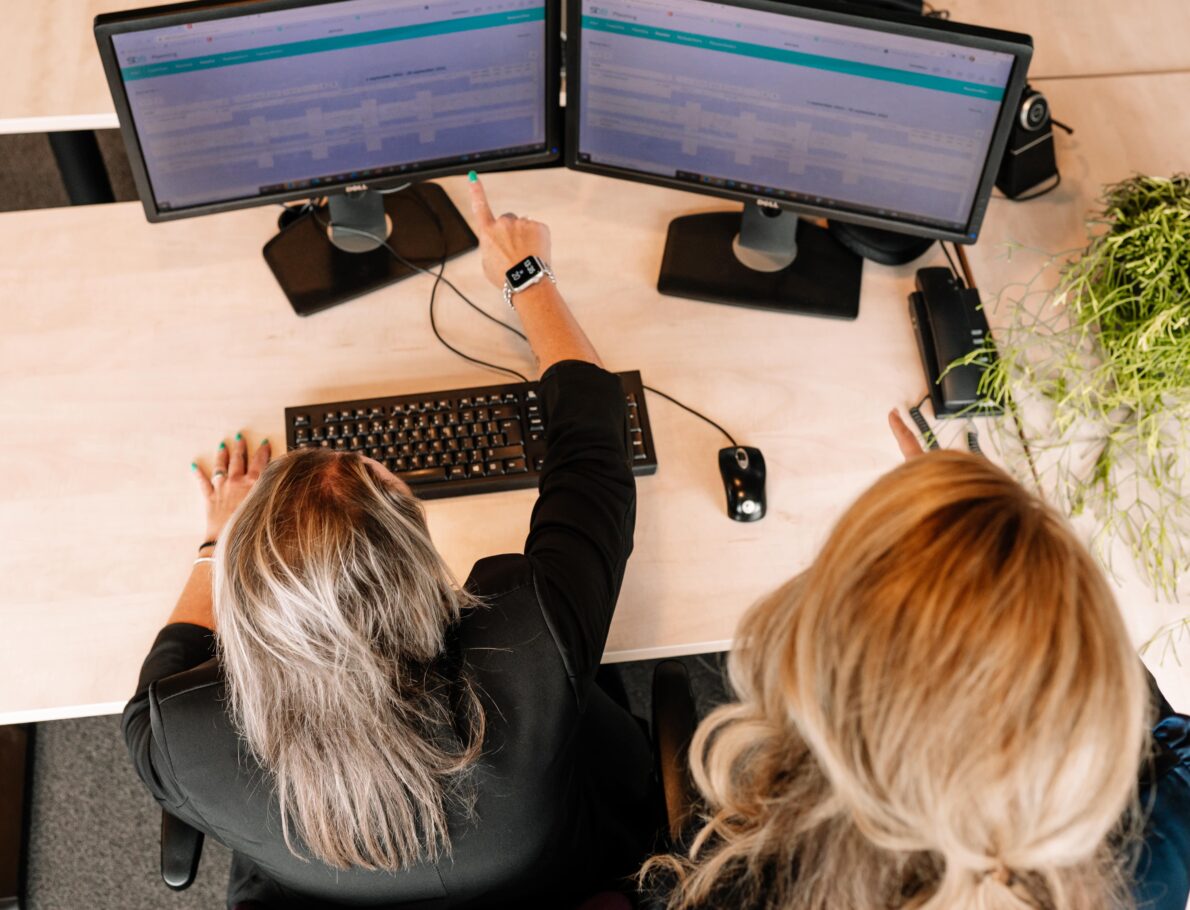 Een Financial Controller aan het overleggen met een collega achter computerschermen