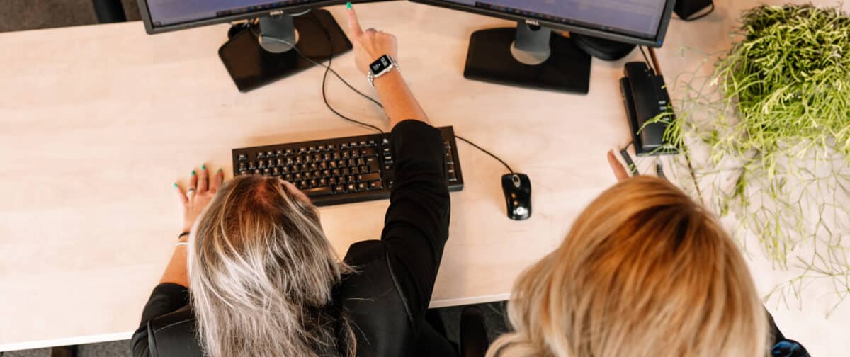 Een Financial Controller aan het overleggen met een collega achter computerschermen